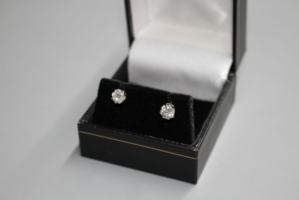 A pair of white metal and solitaire diamond ear studs,